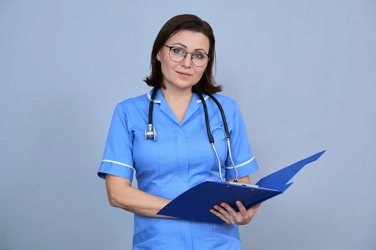 Image of a nurse holding a folder in blue NHS uniform